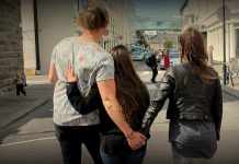 þrír einstaklingar leiðast niður miðbæinn