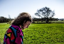 Ungur maður situr á túni og skrifar á blað