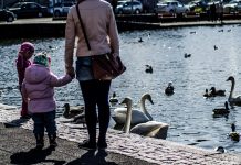 Móðir stendur með barni sínu við tjörnina